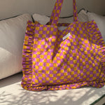 Sac froufrou Moutarde violet posé sur un canapé, damier violet et moutarde, volants sur les côtés