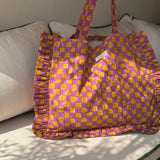 Sac froufrou Moutarde violet posé sur un canapé, damier violet et moutarde, volants sur les côtés