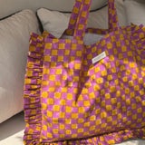 Sac froufrou Moutarde violet à damier, anses longues, étiquette Byzantine, posé au soleil sur un canapé