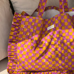 Sac froufrou Moutarde violet de trois quarts, doublure blanche visible, volants à damier