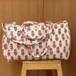Sac weekend matelassé N°50 Rose de Byzantine, petites fleurs roses sur fond écru, posé sur un tabouret en bois