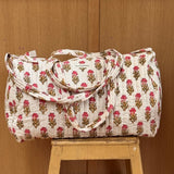Sac weekend matelassé N°50 Rose de Byzantine, petites fleurs roses sur fond écru, posé sur un tabouret en bois