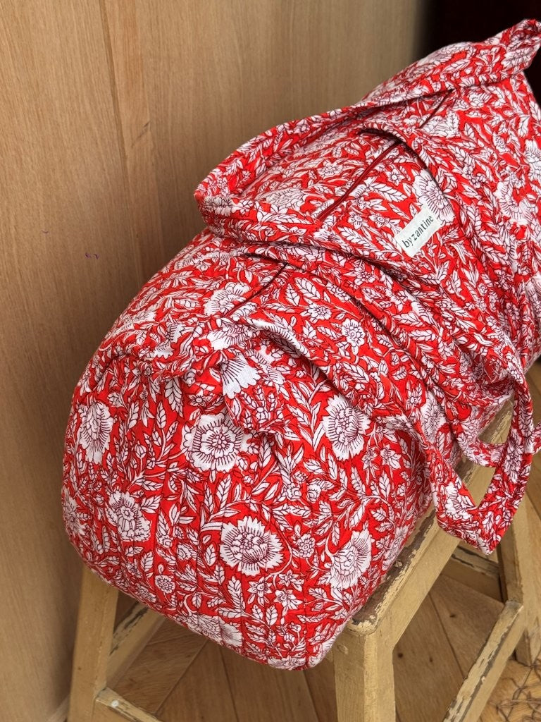 Sac weekend Antioche Tomato sur un tabouret, fleurs blanches sur fond rouge tomate, anses