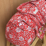 Sac weekend Antioche Tomato sur un tabouret, fleurs blanches sur fond rouge tomate, anses