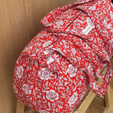 Sac weekend Antioche Tomato sur un tabouret, fleurs blanches sur fond rouge tomate, anses