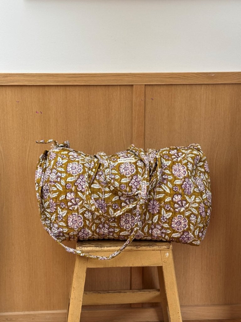 Sac weekend Carthage Kaki posé sur un tabouret, coton matelassé fleuri kaki