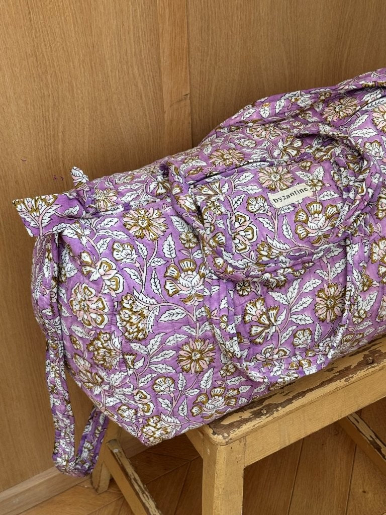 Sac weekend Carthage Lilas sur un tabouret, fleurs écrues sur fond lilas, anses longues