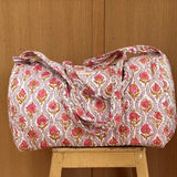 Sac weekend matelassé Éphèse Rose de Byzantine, imprimé fleuri rose, posé sur un tabouret en bois