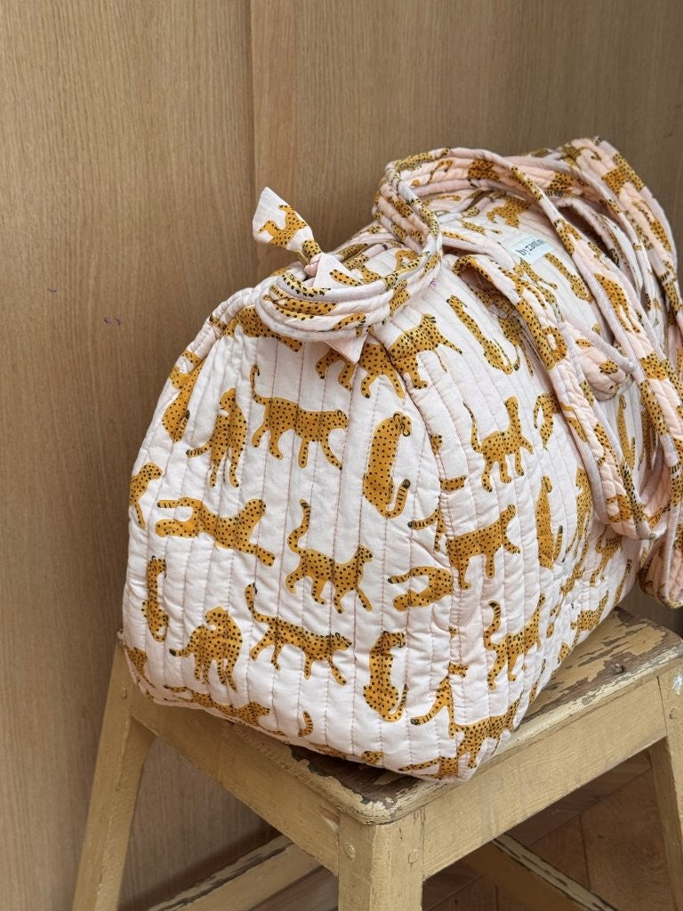 Sac weekend Fauve Rose sur un tabouret, guépards ocre sur fond rose pâle, anses nouées
