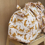 Sac weekend Fauve Rose sur un tabouret, guépards ocre sur fond rose pâle, anses nouées