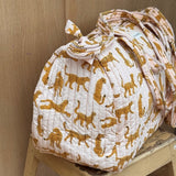 Sac weekend Fauve Rose sur un tabouret, guépards ocre sur fond rose pâle, anses nouées