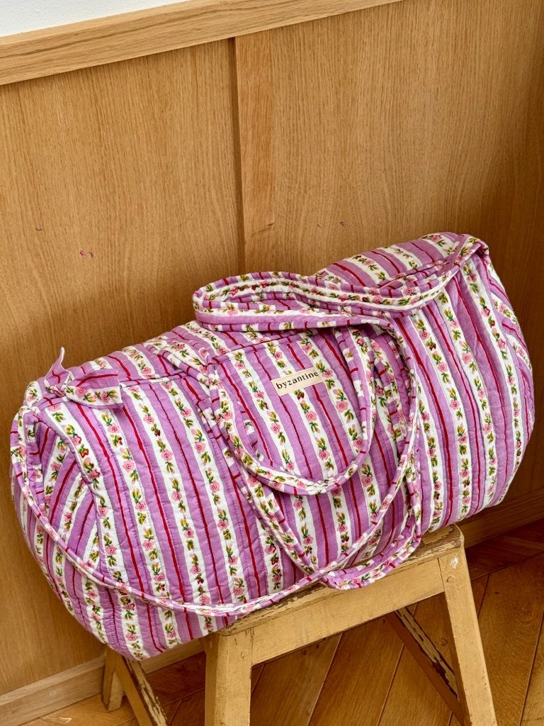 Sac weekend Flora Lilas sur un tabouret, rayures lilas et guirlandes de petites fleurs