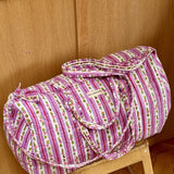 Sac weekend Flora Lilas sur un tabouret, rayures lilas et guirlandes de petites fleurs