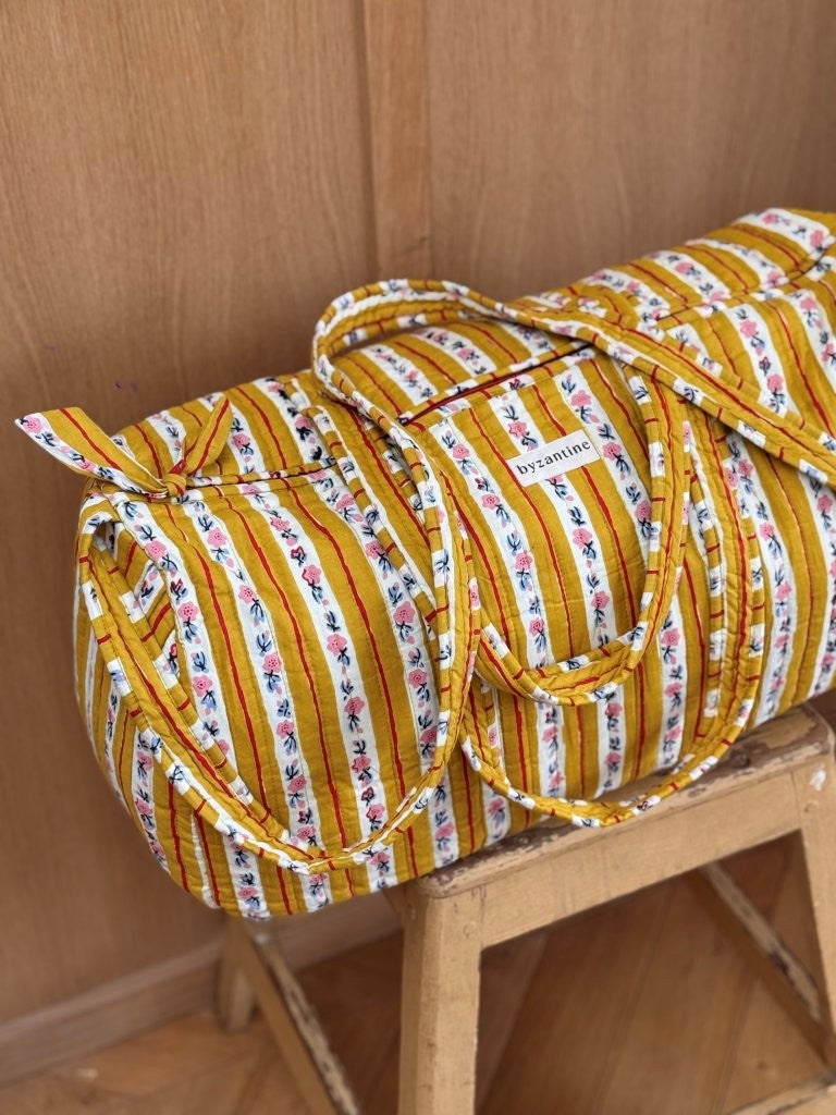 Sac weekend Flora Passion sur un tabouret, rayures jaune moutarde et guirlandes de petites fleurs