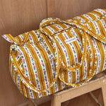 Sac weekend Flora Passion sur un tabouret, rayures jaune moutarde et guirlandes de petites fleurs