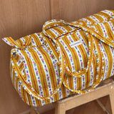 Sac weekend Flora Passion sur un tabouret, rayures jaune moutarde et guirlandes de petites fleurs