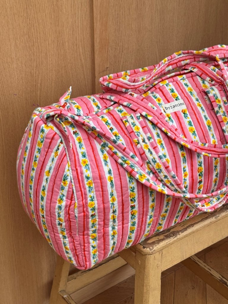 Sac weekend Flora Rose sur un tabouret, rayures roses et guirlandes de petites fleurs jaunes