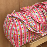 Sac weekend Flora Rose sur un tabouret, rayures roses et guirlandes de petites fleurs jaunes
