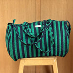 Sac weekend matelassé Pacha Menthe de Byzantine, rayures vert menthe et bleu nuit, posé sur un tabouret en bois