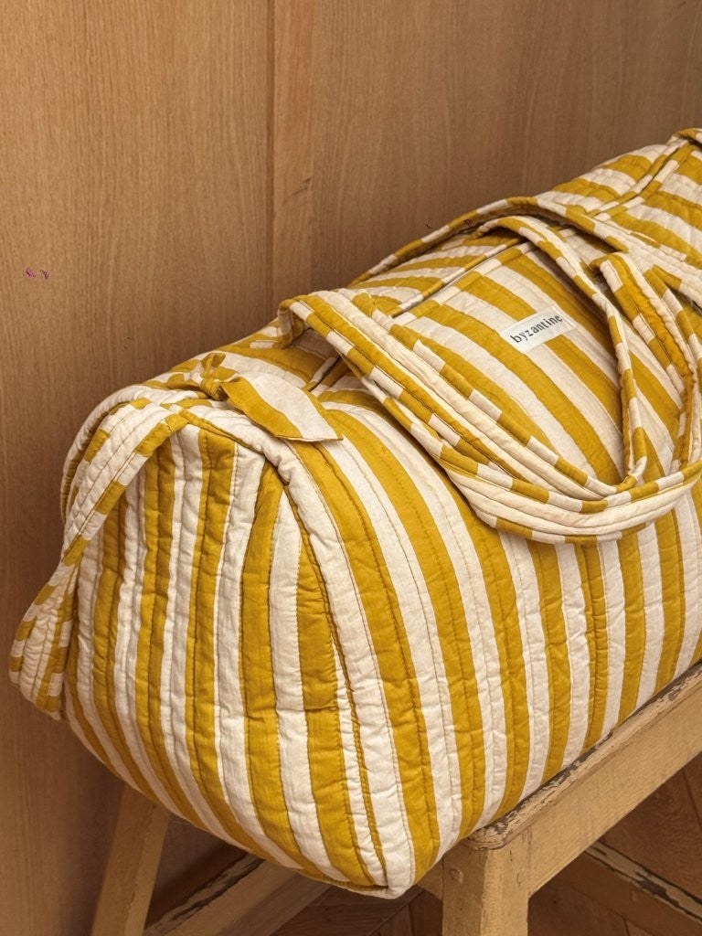 Sac weekend Pacha Passion sur un tabouret, larges rayures moutarde et écru