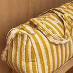 Sac weekend Pacha Passion sur un tabouret, larges rayures moutarde et écru