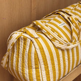 Sac weekend Pacha Passion sur un tabouret, larges rayures moutarde et écru