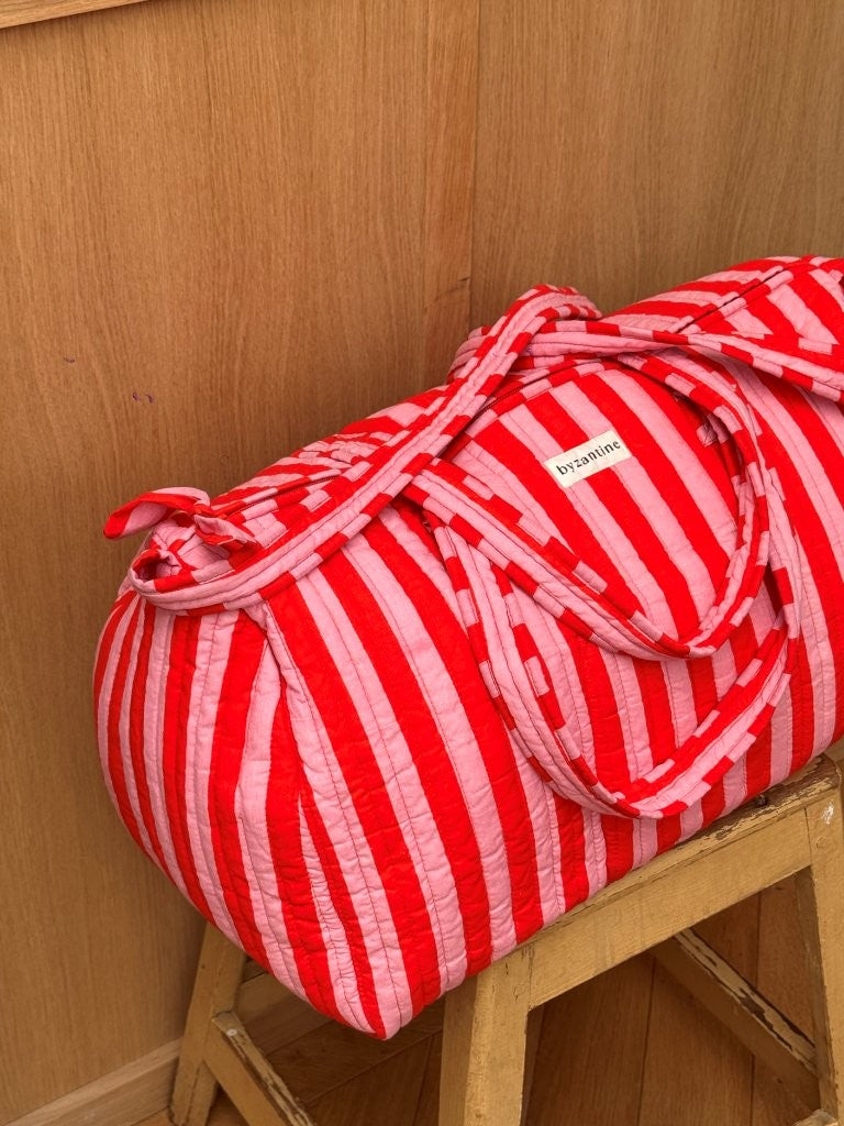 Sac weekend Pacha Tomato sur un tabouret, anses nouées, larges rayures rouges et roses