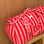 Sac weekend Pacha Tomato sur un tabouret, anses nouées, larges rayures rouges et roses