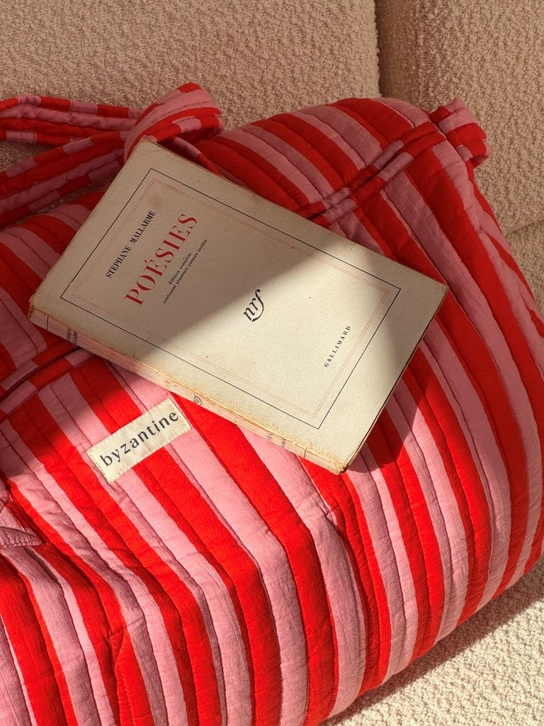 Gros plan sur le sac weekend Pacha Tomato, livre posé dessus et étiquette Byzantine