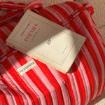 Gros plan sur le sac weekend Pacha Tomato, livre posé dessus et étiquette Byzantine