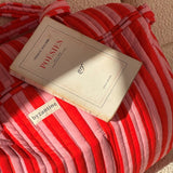Gros plan sur le sac weekend Pacha Tomato, livre posé dessus et étiquette Byzantine