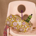 Trousse à crayons Carthage Kaki ouverte avec brosse à dents et tube, sur une chaise rose
