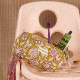 Trousse à crayons Carthage Kaki ouverte avec brosse à dents et tube, sur une chaise rose