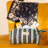 Petite trousse à crayons Flora Bleu marine remplie de soins, sur un fauteuil moutarde