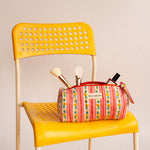 Trousse à crayons Flora Rose avec pinceaux de maquillage, posée sur une chaise jaune