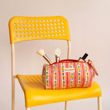 Trousse à crayons Flora Rose avec pinceaux de maquillage, posée sur une chaise jaune
