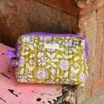 Trousse de toilette XL Carthage Kaki posée sur un banc, étiquette Byzantine et passepoil violet