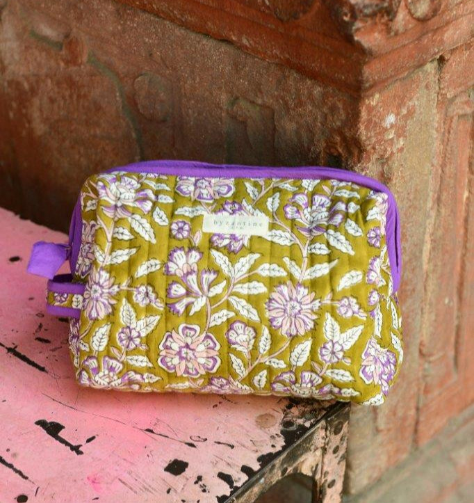 Trousse de toilette XL Carthage Kaki posée sur un banc, étiquette Byzantine et passepoil violet