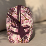 Trousse de toilette XL Carthage Prune de côté sur un canapé, poche latérale et nœud prune