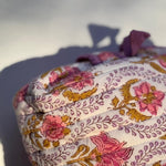 Détail du coton matelassé imprimé Éphèse Rose, fleurs rose et moutarde sur fond écru