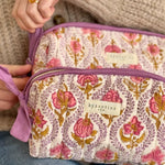 Mains ouvrant le zip de la trousse de toilette XL Éphèse Rose, étiquette Byzantine