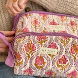 Mains ouvrant le zip de la trousse de toilette XL Éphèse Rose, étiquette Byzantine