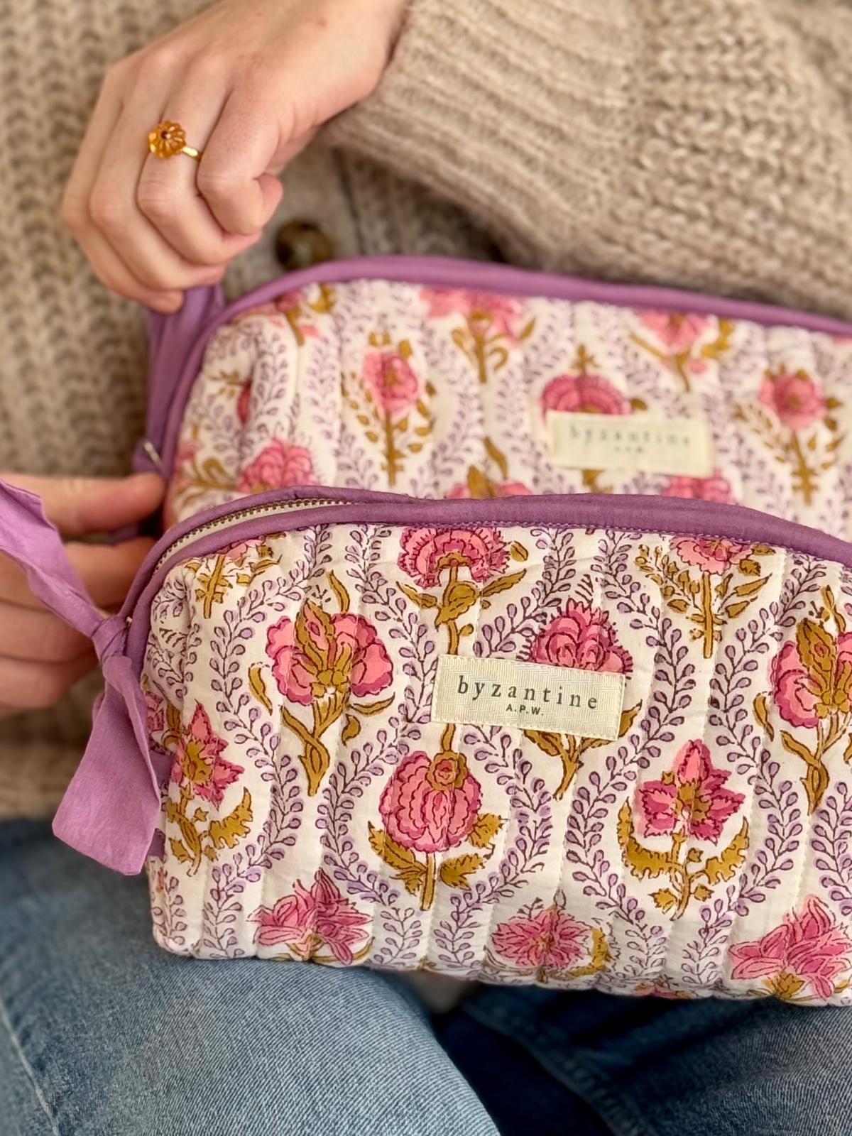 Mains ouvrant le zip de la trousse de toilette XL Éphèse Rose, étiquette Byzantine