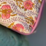 Gros plan sur l'imprimé fleuri Éphèse Rose, roses corail et rinceaux lilas, bord passepoilé
