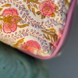 Gros plan sur l'imprimé fleuri Éphèse Rose, roses corail et rinceaux lilas, bord passepoilé