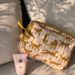 Trousse de toilette XL Fauve Rose de Byzantine avec un tube de crème, posée sur un coussin
