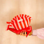 Trousse froufrou Pacha Tomato tenue à la main, rayures rouge et rose