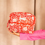 Grande trousse de toilette à rabat festonné Antioche Tomato tenue à bout de bras, manche rose