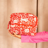 Grande trousse de toilette à rabat festonné Antioche Tomato tenue à bout de bras, manche rose
