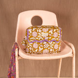Trousse rabat Carthage Kaki à bord festonné violet, sur une chaise rose avec un foulard